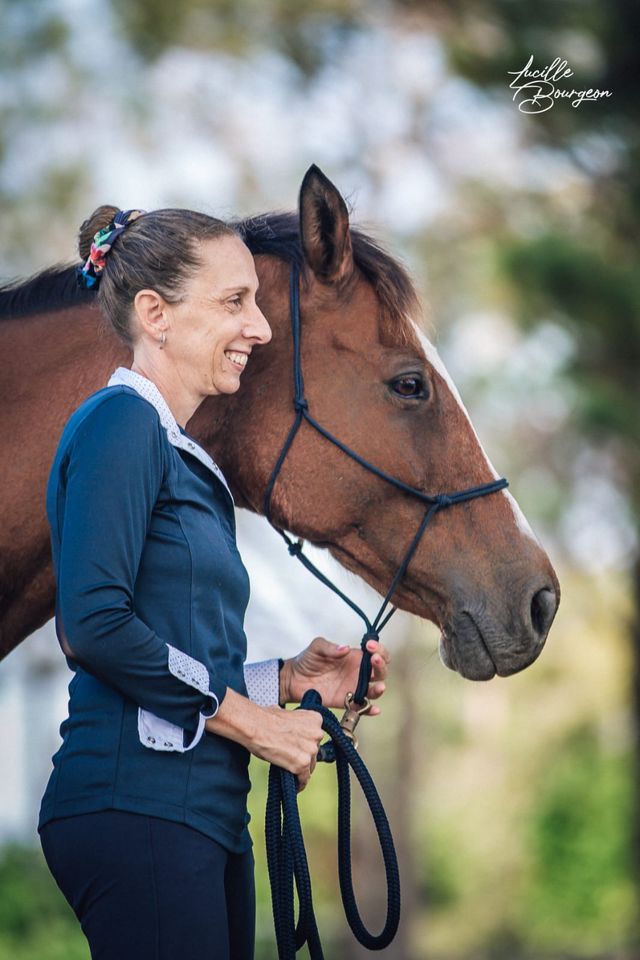 Cavalière souriante joue contre joue avec son cheval sous les arbres